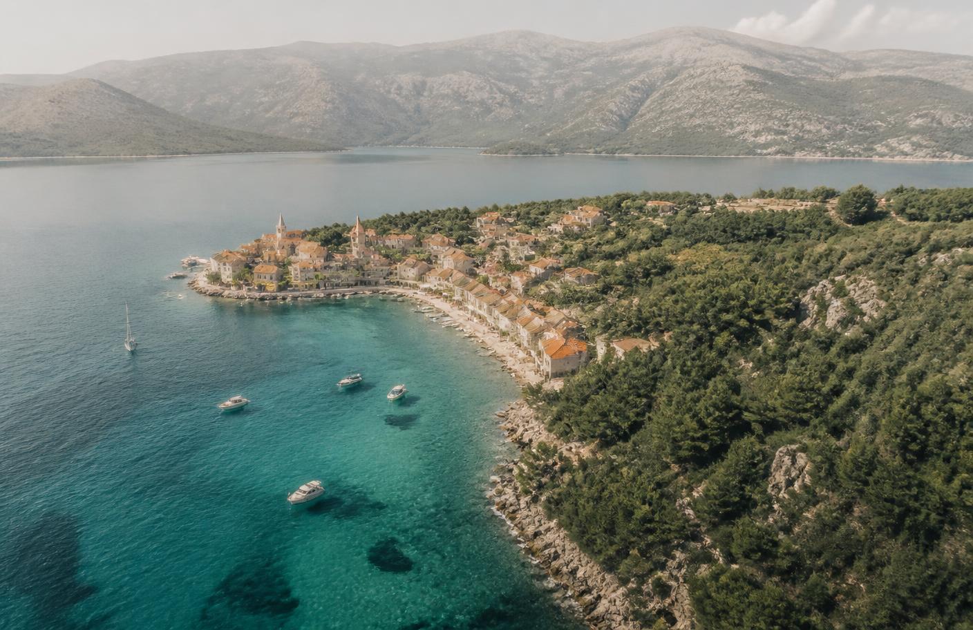 Vista aérea de un pueblo costero de Dalmacia sobre agua turquesa
